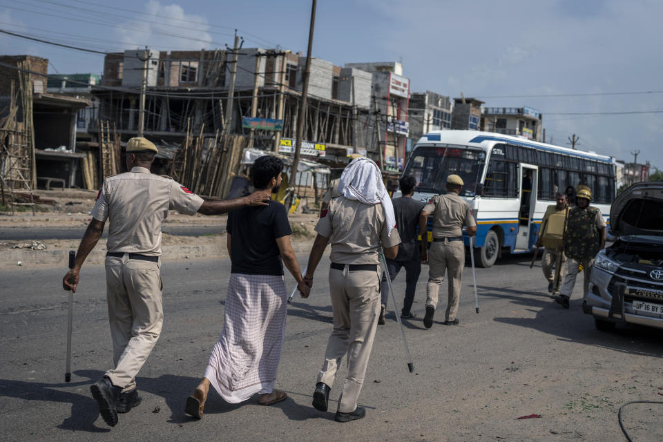 Policemen detain people after communal clashes in Nuh in Haryana state, India, Tuesday, Aug., 1, 2023. Deadly clashes between Hindus and Muslims began in the area Monday afternoon during a religious procession by a Hindu nationalist group forcing Indian authorities to impose a curfew and suspend Internet services. (AP Photo/Altaf Qadri)