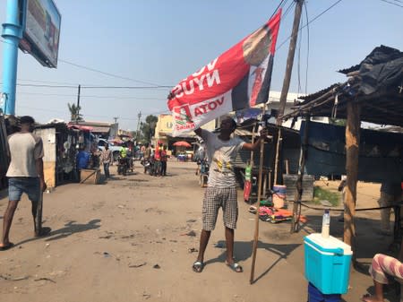 A man stretches out a campaign flag for President Filipe Nyusi at a market in Beira