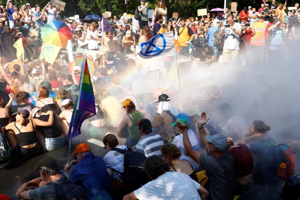 People are sprayed by a water cannon, as climate activists block the A12 highway in The Hague, Netherlands (REUTERS)