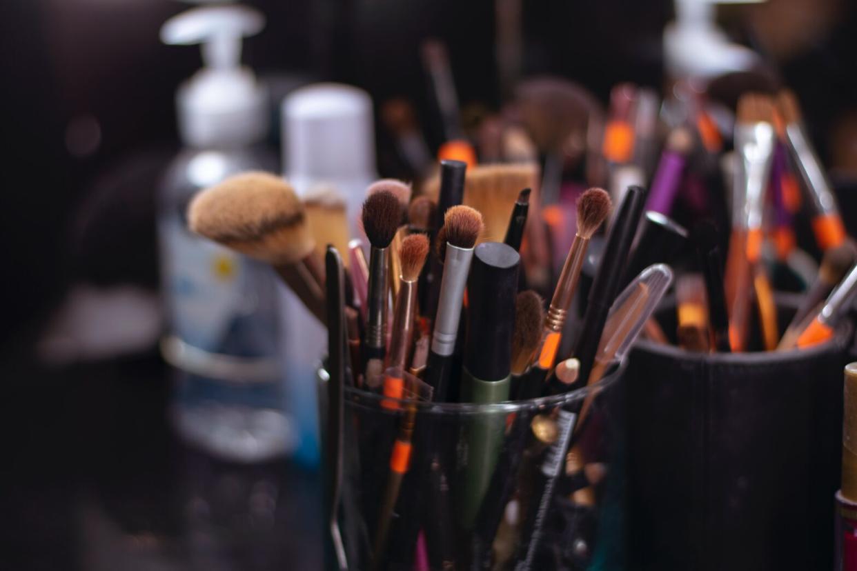 used makeup brushes in containers on a black desk