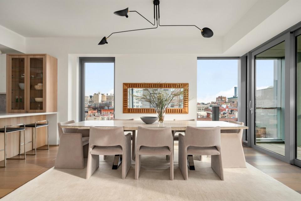 A sunny great room opens to the kitchen, as light streams in through floor-to-ceiling windows. Courtesy of property