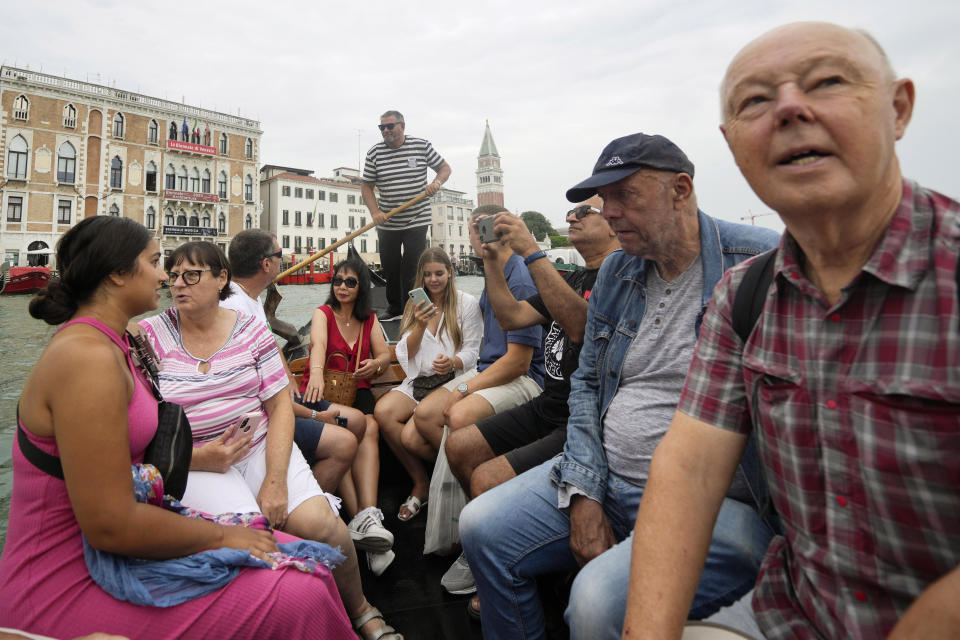 Tourists sit in a gondola during a short crossing of a canal, in Venice, Italy, Wednesday, Sept. 13, 2023. The Italian city of Venice has been struggling to manage an onslaught of tourists in the budget travel era. The stakes for the fragile lagoon city are high this week as a UNESCO committee decides whether to insert Venice on its list of endangered sites. (AP Photo/Luca Bruno)