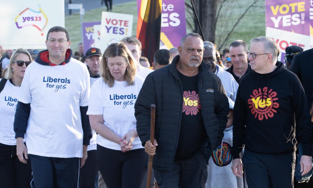 Julian Leeser, Bridget Archer, Michael Long and Anthony Albanese walking wearing tops with slogans supporting a yes vote