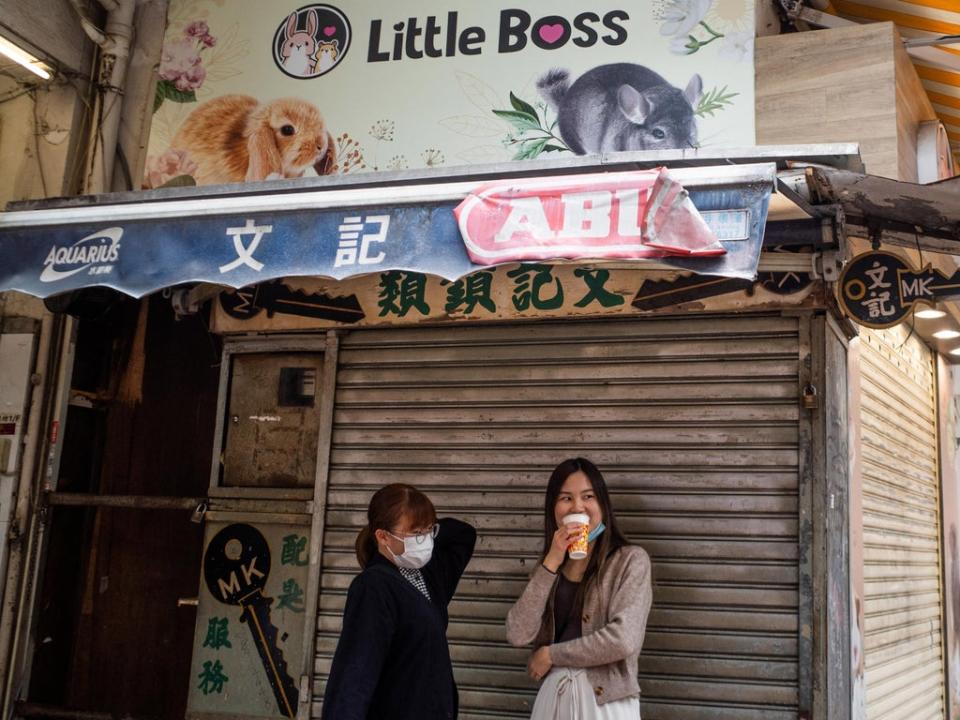 People stand under a banner for a pet shop where an employee and a customer later tested positive for Covid-19 after handling hamsters (AFP via Getty Images)