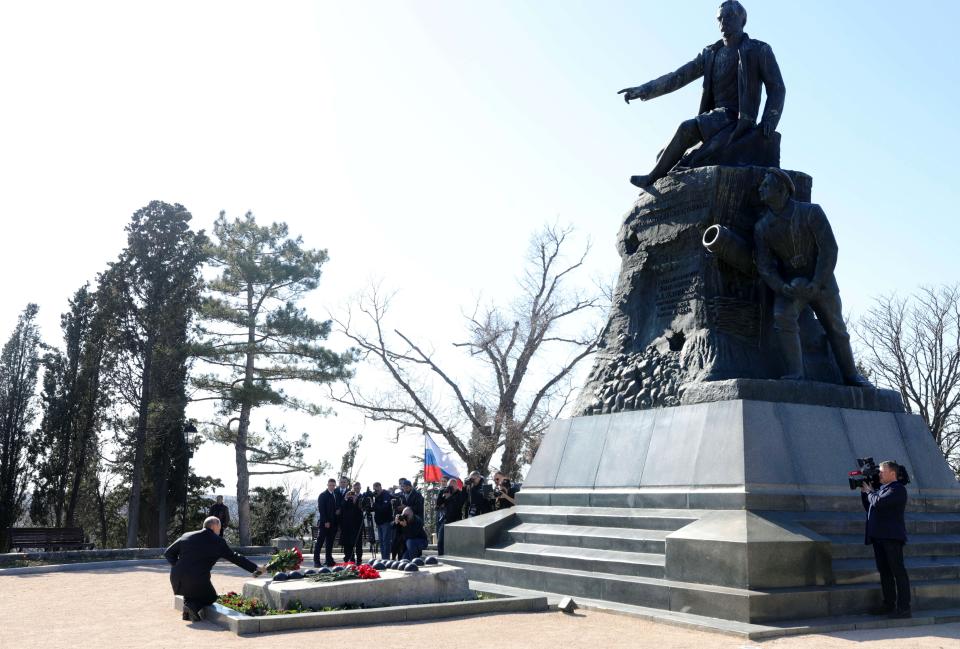 Russian President Vladimir Putin, left, puts a bunch of flowers to the monument to Vice-Admiral Vladimir Kornilov at the historical memorial the Malakhov Kurgan (Malakoff redoubt) in Sevastopol, Crimea, Monday, March 18, 2019. Putin visited Crimea to mark the fifth anniversary of Russia's annexation of Crimea from Ukraine by visiting the Black Sea peninsula. (Mikhail Klimentyev, Sputnik, Kremlin Pool Photo via AP)