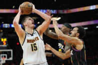 Denver Nuggets center Nikola Jokic (15) shoot over Phoenix Suns guard Landry Shamet, right, and forward Torrey Craig, center, during the second half of Game 6 of an NBA basketball Western Conference semifinal game, Thursday, May 11, 2023, in Phoenix. The Nuggets eliminated the Sun in their 125-100 win. (AP Photo/Matt York)