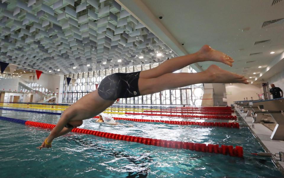 A visitor dives into a swimming pool at Aquatic Sports Palace, an aquatic centre which includes a water park, swimming pools and a surf point, at the Luzhniki Olympic Sports Complex - Getty Images