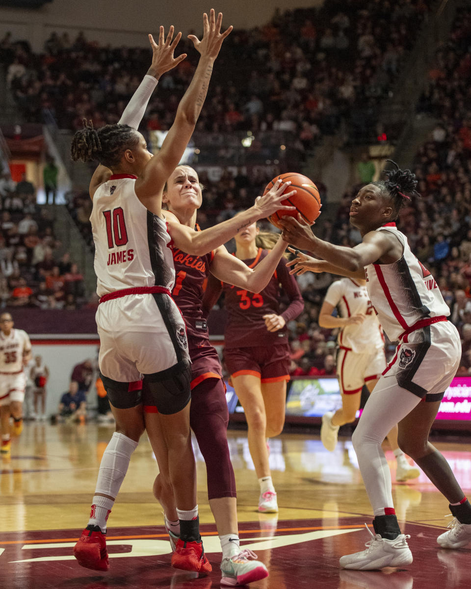 Virginia Tech's Carleigh Wenzel, center, drives the lane against NC State's Aziaha James during the second half of an NCAA college basketball game, Sunday, Jan. 7, 2024, in Blacksburg, Va. (AP Photo/Robert Simmons)