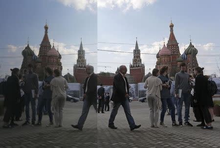 People are seen in a reflection as they gather near St. Basil's Cathedral (R) and the Kremlin in central Moscow, April 29, 2014. REUTERS/Maxim Shemetov