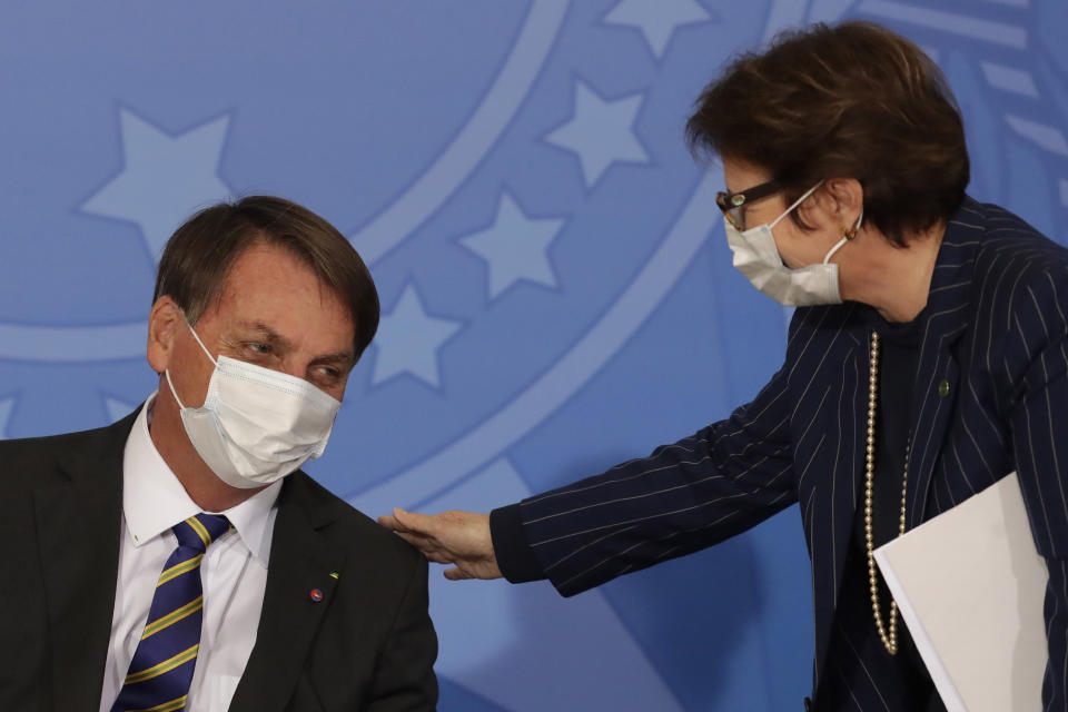 Brazil's President Jair Bolsonaro wearing a protective mask to curb the spread of the new coronavirus, left, talks with Agriculture Minister Tereza Cristina during the launching ceremony of a rights guarantee program for rural women, at the Planalto Presidential Palace in Brasilia, Brazil, Wednesday, July 29, 2020. (AP Photo/Eraldo Peres)