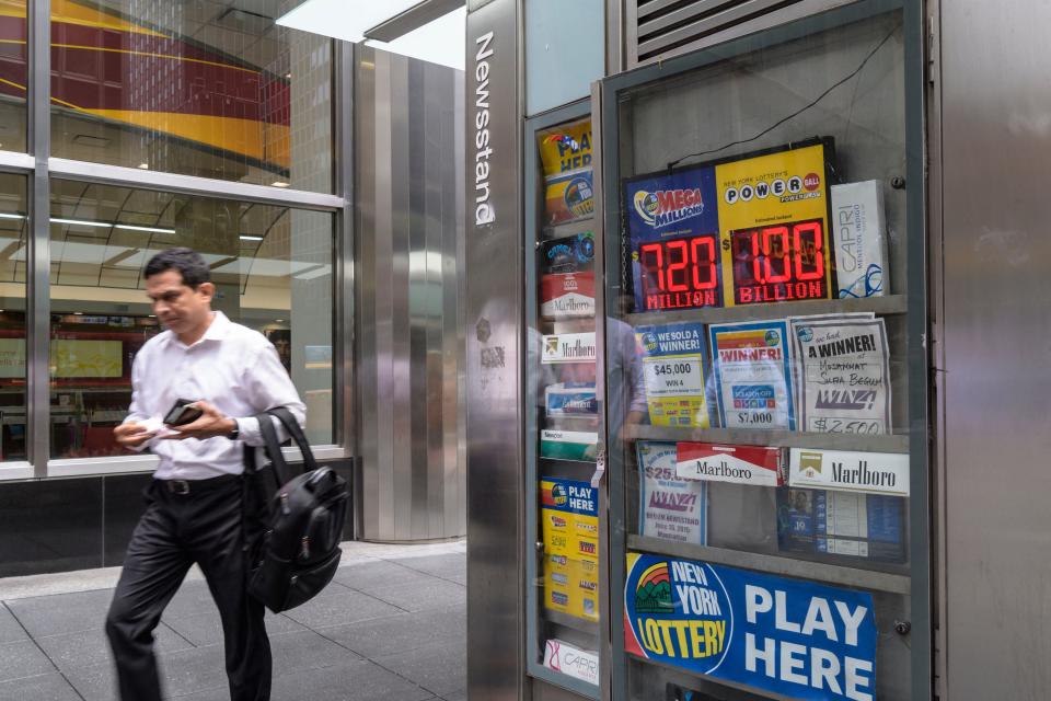 A person walks past a news stand after purchasing lottery tickets Wednesday in New York City.