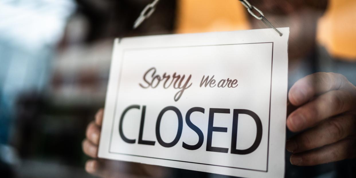 Business owner holding closed sign on storefront door