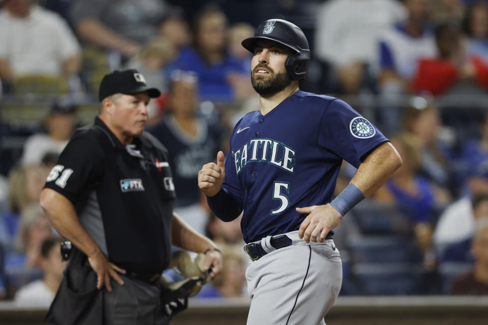 Seattle Mariners' Curt Casali crosses home plate to score on a Ty France single as umpire Marvin Hudson, left, watches during the fourth inning of the team's baseball game against the Kansas City Royals in Kansas City, Mo., Saturday, Sept. 24, 2022. (AP Photo/Colin E. Braley)