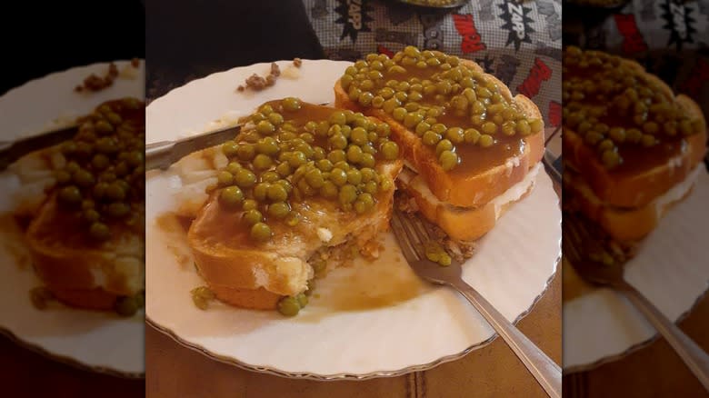 Meat sandwich covered with peas and gravy 