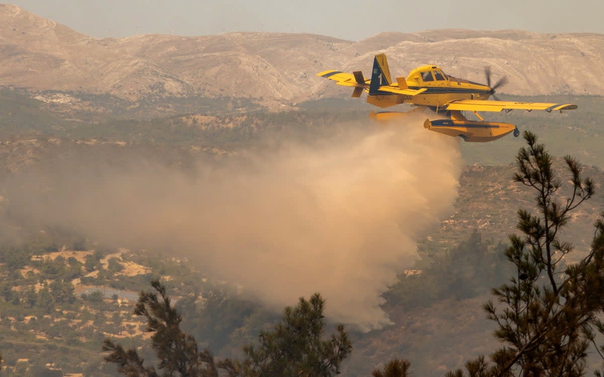 A firefighting plane drops water over a wildfire burning near Asklipio on the island of Rhodes, Greece on Sunday July 23  (Lefteris Damianidis/Reuters)