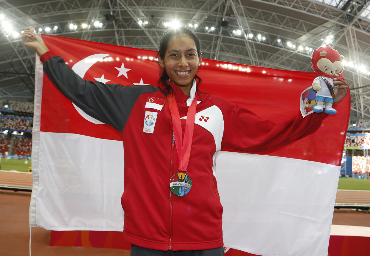 Singapore’s Dipna Lim-Prasad holds the national flag after coming in second in the 400m hurdles race at the 2015 SEA Games (FILE PHOTO: Singapore SEA Games Organising Committee/Reuters)