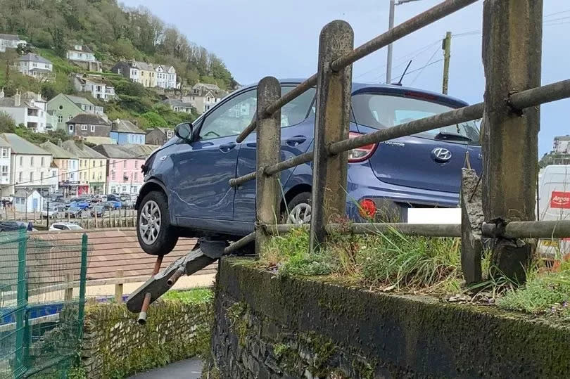 A car was left hanging from a road in West Looe after crashing into a railing