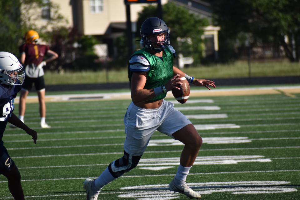 Decatur Central quarterback Aycen Stevens evades Castle's defense during the Hawks' four-way scrimmage with the Knights, Bloomington North and Speedway on June 23, 2022.