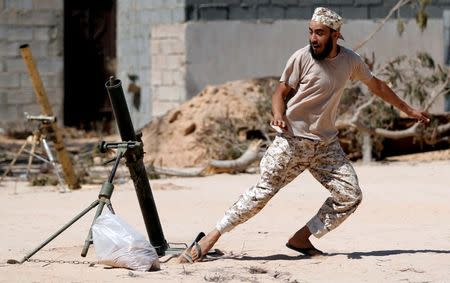 A fighter of Libyan forces allied with the U.N.-backed government fires a 81 mm mortar round in Sirte, Libya. REUTERS/Goran Tomasevic