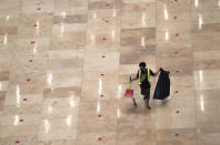 A cleaner walks between lines of praying position markers to maintain physical distancing during prayers amid the new coronavirus outbreak, at Istiqlal Mosque in Jakarta, Indonesia, Wednesday, June 3, 2020. (AP Photo/Achmad Ibrahim)