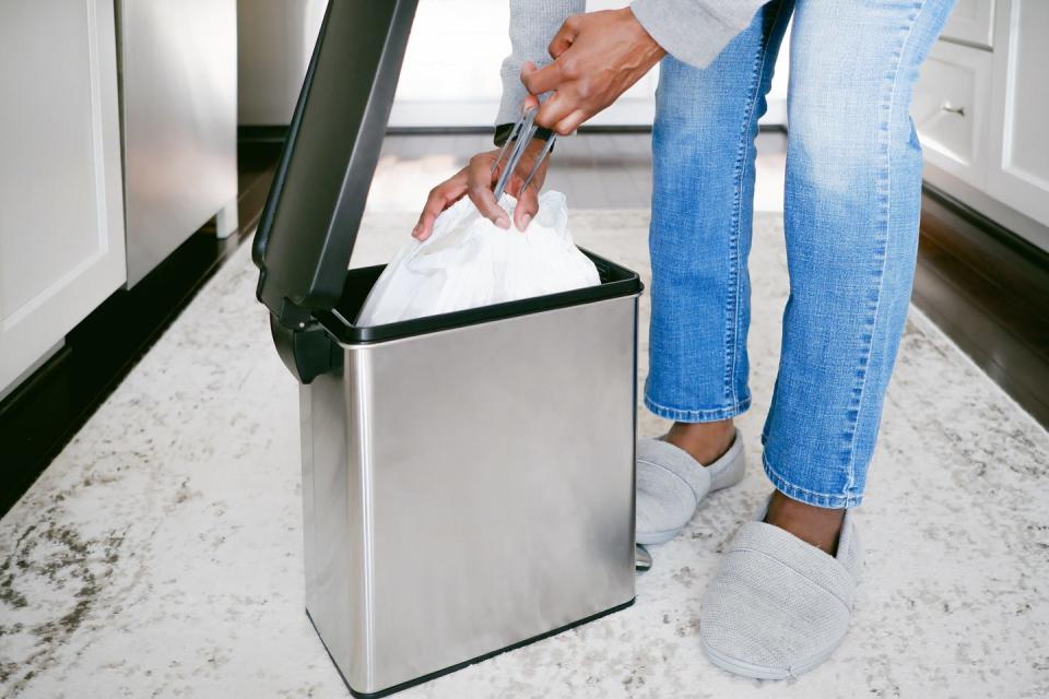 Woman takes garbage bag out of the bin