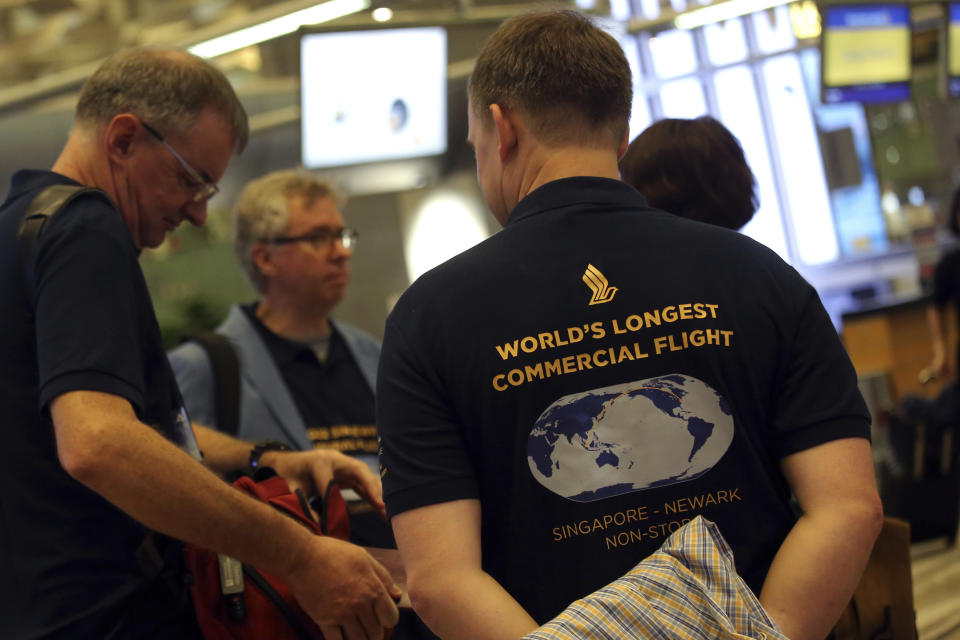 Passengers wearing self designed t-shirts which celebrate their trip on Singapore Airline's inaugural non-stop flight to New York, wait at the check-in counter on Thursday, Oct. 11, 2018, in Singapore. The world's longest flight is taking travelers from Singapore to New York. Operated by Singapore Airlines, the city-state's national carrier, the trip will take less than 19 hours. Skipping a stopover in Frankfurt shaves as much as 6 hours off traveling time, the carrier said. (AP Photo/Wong Maye-E)