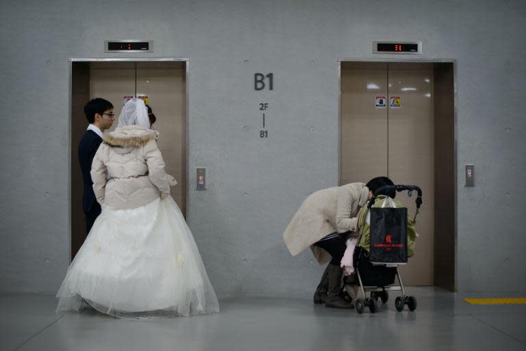 A newly-wed couple wait for an elevator at a mass wedding event held by the Unification Church, in Gapyeong, South Korea, on February 12, 2014
