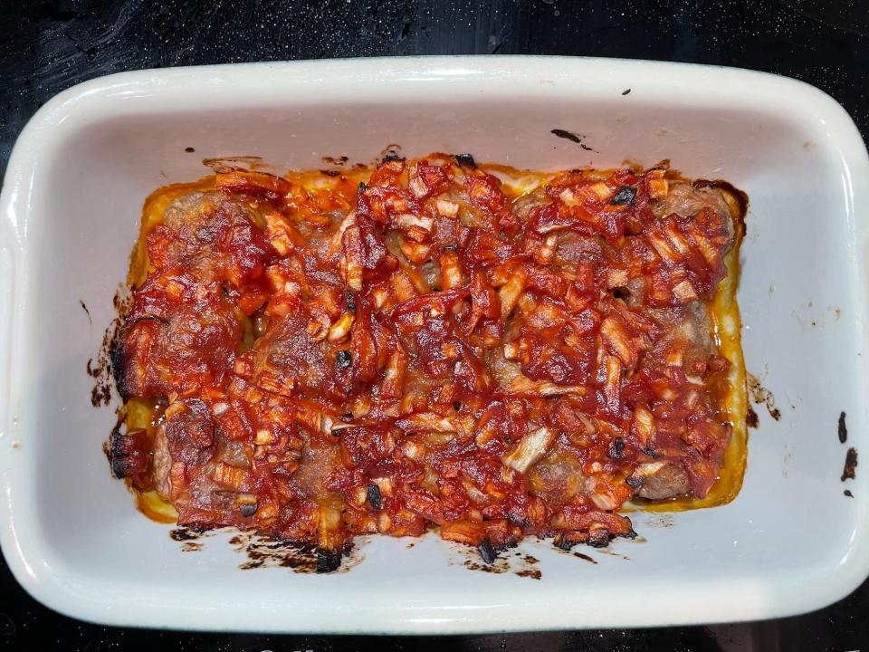 meatballs covered with an onion-ketchup sauce in a ceramic baking dish