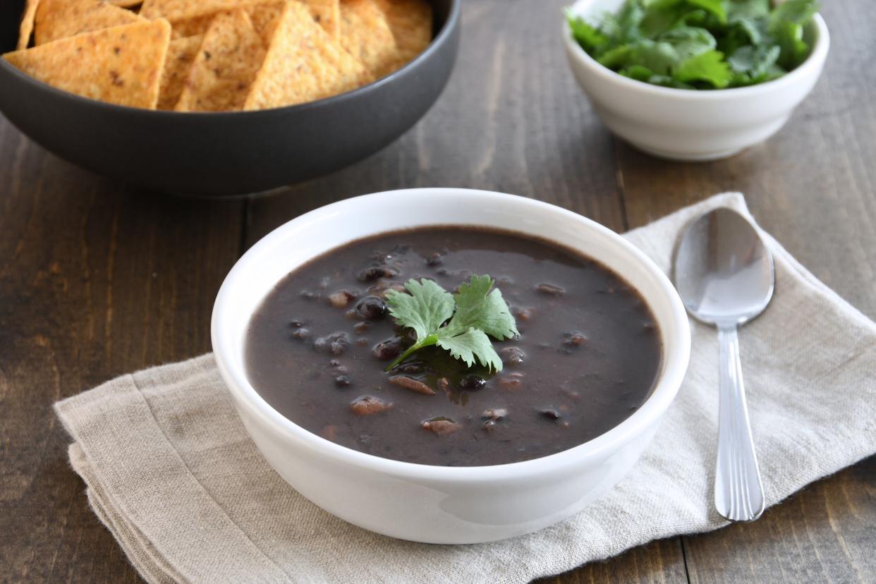 Healthy, hearty bowl of black bean and pinto bean soup shown with tortilla chips and cilantro