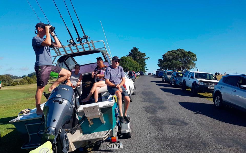 John Fitzgerald, left, on holidays with his wife Rita and friends, scans the horizon from high ground for any sign of a tsunami near Waitangi, New Zealand - AP