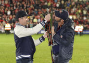 Wrexham co-owners Rob McElhenney, left, and Ryan Reynolds celebrate with the trophy after their team clinched promotion following the National League soccer match between Wrexham and Boreham Wood at The Racecourse Ground, in Wrexham, Wales, Saturday April 22, 2023. (Martin Rickett/PA via AP)