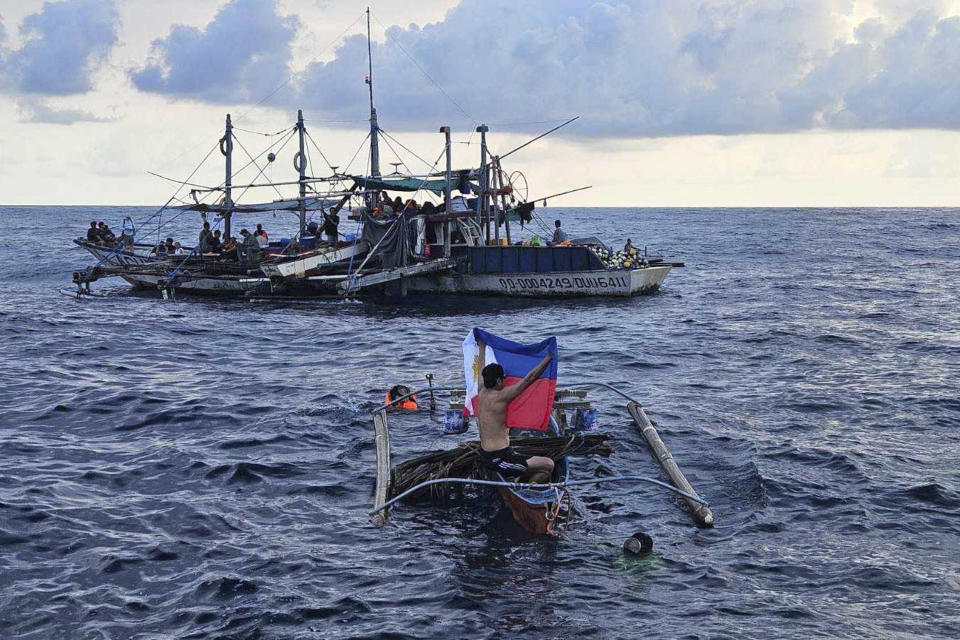 In this photo provided by Atin-Ito/Akbayan Party, a fisherman raises a Philippine flag on his boat as activists and volunteers from a nongovernment coalition called Atin Ito, Tagalog for This is Ours, sailed at the South China Sea on Thursday May 16, 2024. About 100 Filipino activists on wooden boats have decided not to sail closer to a fiercely disputed shoal in the South China Sea on Thursday to avoid a confrontation with dozens of Chinese coast guard and suspected militia ships guarding the area. (Atin-Ito/Akbayan Party via AP)