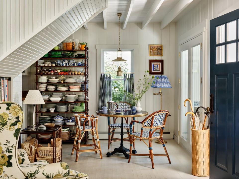 breakfast room of a rhode island cottage with a small bistro dining table, etegere full of mismatched colorful plates