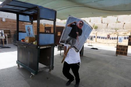 A tourist carries a poster as he takes part in a two hour "boot camp" experience, at "Caliber 3 Israeli Counter Terror and Security Academy" in the Gush Etzion settlement bloc south of Jerusalem in the occupied West Bank July 13, 2017. Picture taken July 13, 2017. REUTERS/Nir Elias