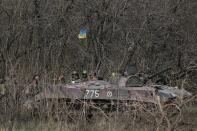 Ukrainian army troops stand next to an armored vehicle with a Ukrainian flag on the outskirts of Izyum, Eastern Ukraine, Tuesday, April 15, 2014. An Associated Press reporter saw at least 14 armored personnel carriers with Ukrainian flags, one helicopter and military trucks parked 40 kilometers (24 miles) north of the city of Slovyansk on Tuesday. (AP Photo/Sergei Grits)