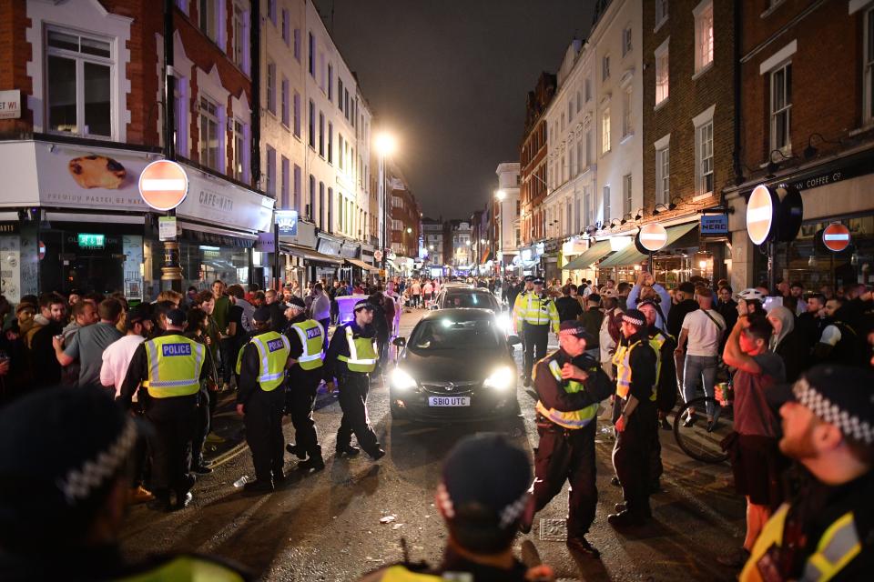 Police officers move revellers from the road to allow traffic to pass in the Soho area of London on July 4, 2020, after the police re-opened the road at 2300 following a further easing of restrictions to allow pubs and restaurants to open during the novel coronavirus COVID-19 pandemic. - Pubs in England reopen on Saturday for the first time since late March, bringing cheer to drinkers and the industry but fears of public disorder and fresh coronavirus cases. (Photo by JUSTIN TALLIS / AFP) (Photo by JUSTIN TALLIS/AFP via Getty Images)