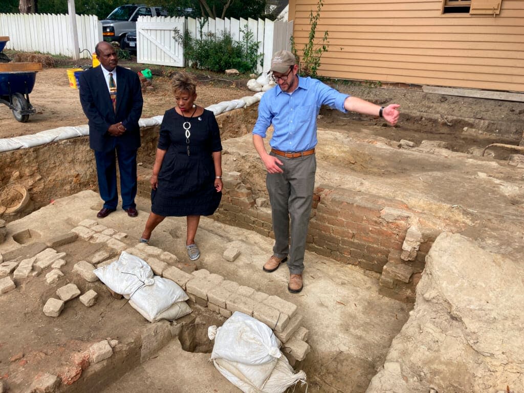 Reginald F. Davis, from left, pastor of First Baptist Church, Connie Matthews Harshaw, a member of First Baptist, and Jack Gary, Colonial Williamsburg’s director of archaeology, stand at the brick-and-mortar foundation of one the oldest Black churches in the U.S. on Oct. 6, 2021, in Williamsburg, Va.(AP Photo/Ben Finley, File)