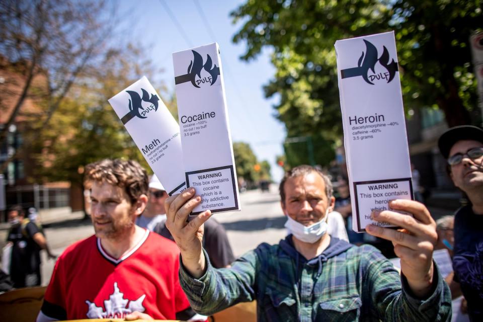 A man holds boxes containing cocaine, meth and heroin that was given out by Jean Swanson during a safe supply event in Vancouver, B.C. on Wednesday, July 14, 2021. 