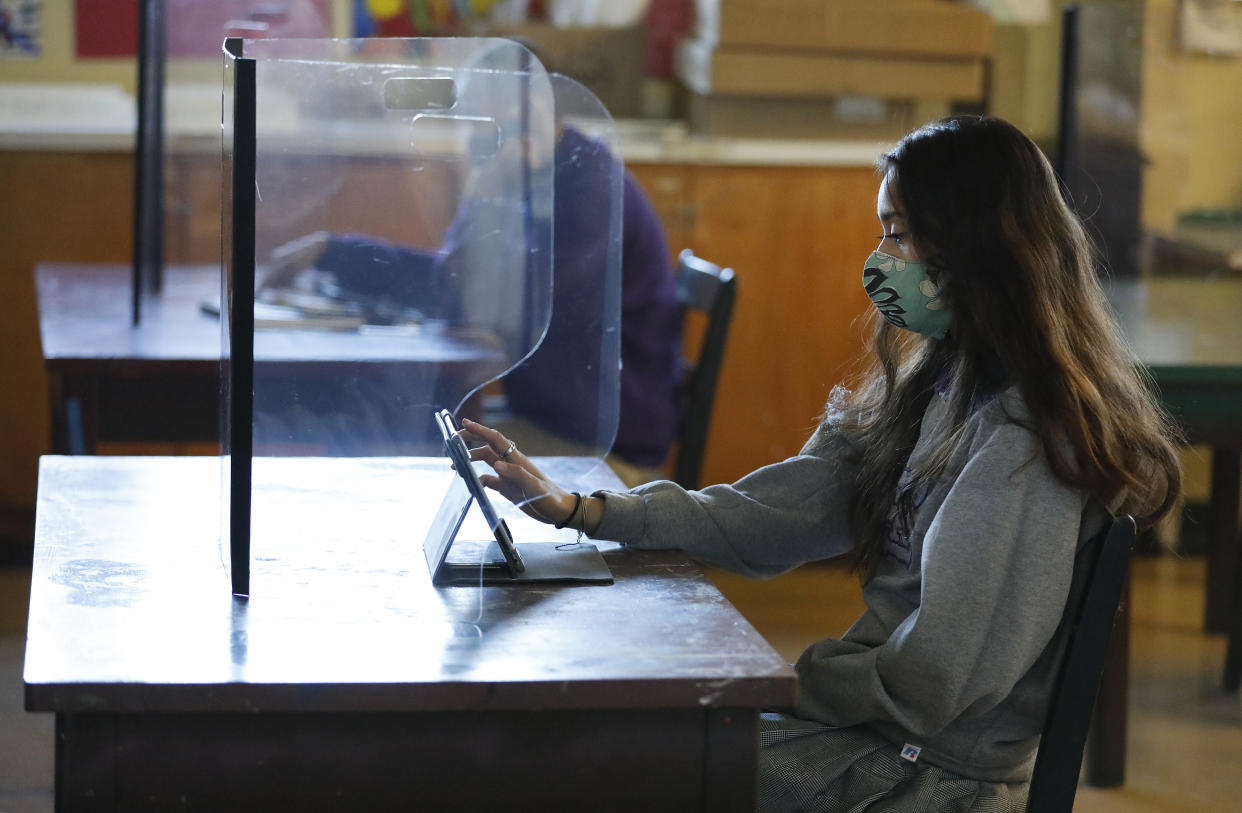 LONG BEACH, CA - MARCH 24:                                                       Senior student Ariana Diaz with a plexiglass barrier in the art classroom of Art 2 teacher Patty Steponovich as students return to in-person instruction at St. Anthony Catholic High School in Long Beach March 24, 2021. The students have not returned to campus since March 2020 due to the Covid-19 pandemic. The hybrid model that will be used at St. Anthony's will allow 60% of the school's 445 students to return for full-time, in-person instruction and splitting those to rotating days so roughly 134 students per day on campus, while also continuing remote learning for those who opt to remain at home. On campus Covid-19 safety measures include temperature checks, face masks, social distancing and plexiglass barriers around desks. President of St. Anthony High School Gina Maguire says they are working to get all students back on campus by May.     St. Anthony Catholic High School on Wednesday, March 24, 2021 in Long Beach, CA. (Al Seib / Los Angeles Times via Getty Images). 