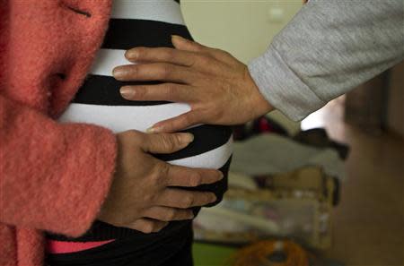 Lu Libing touches the belly of his pregnant wife, Mu, as they pose for pictures during an interview with Reuters at their home in Ganzhou, Jiangxi province March 13, 2014. REUTERS/Alex Lee