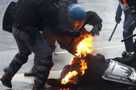 Policemen help their colleague caught on fire after being hit by a molotov bomb during a rally against Expo 2015 in Milan, May 1, 2015. REUTERS/Stefano Rellandini