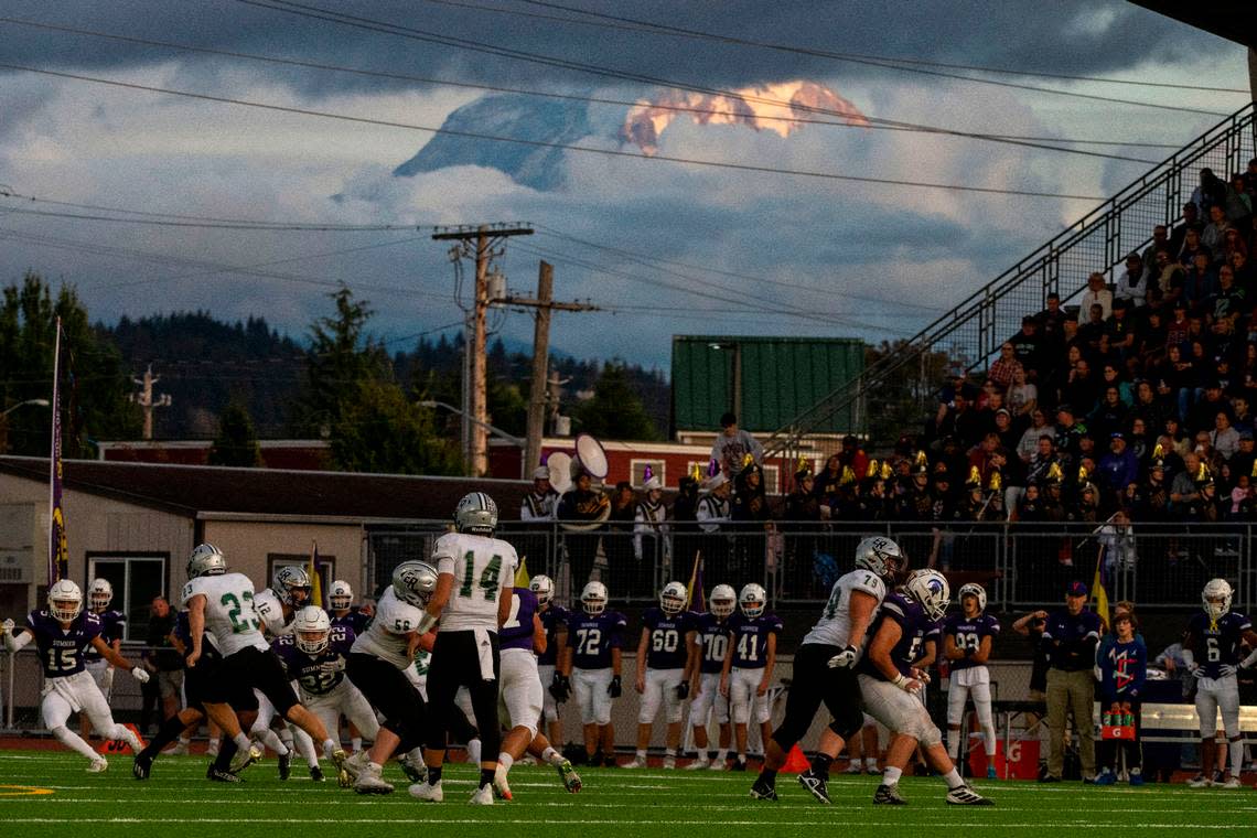 Mount Rainier peaks out through the clouds as Emerald Ridge running back Logan Lisherness carries the ball through the Sumner defense during the first quarter of a 4A SPSL game on Friday, Sept. 16, 2022, at Sunset Chev Stadium in Sumner, Wash.