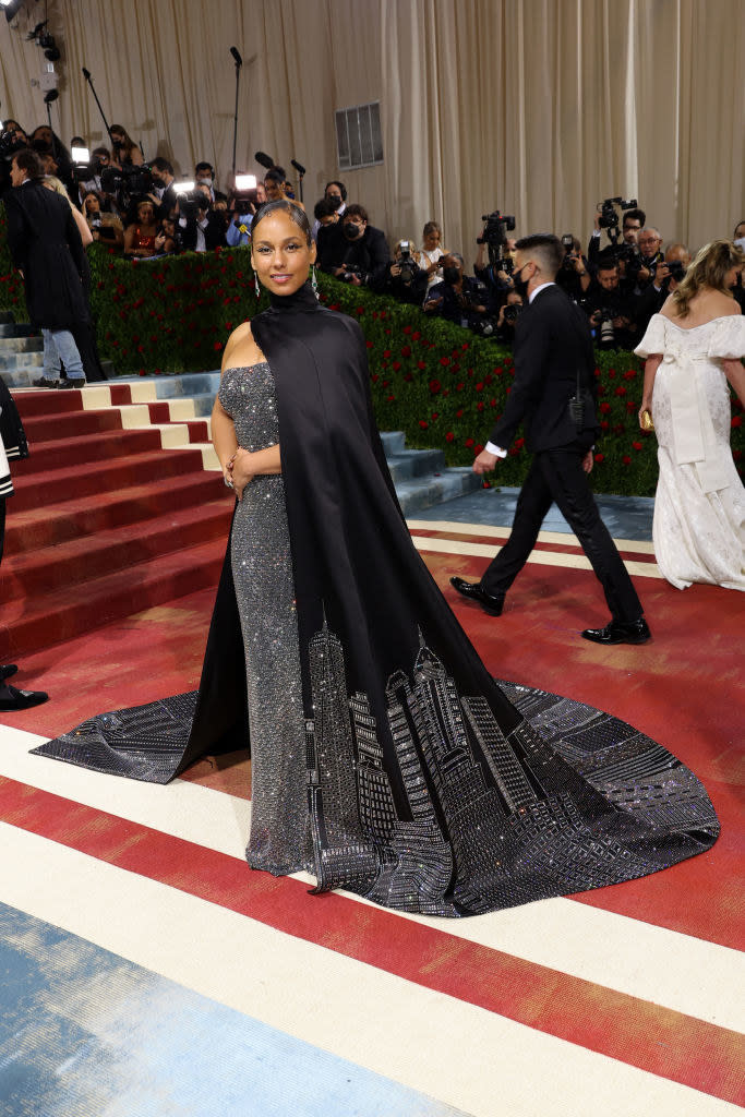 Alicia Keys smiling and wearing a dress overlooking the city skyline on her train