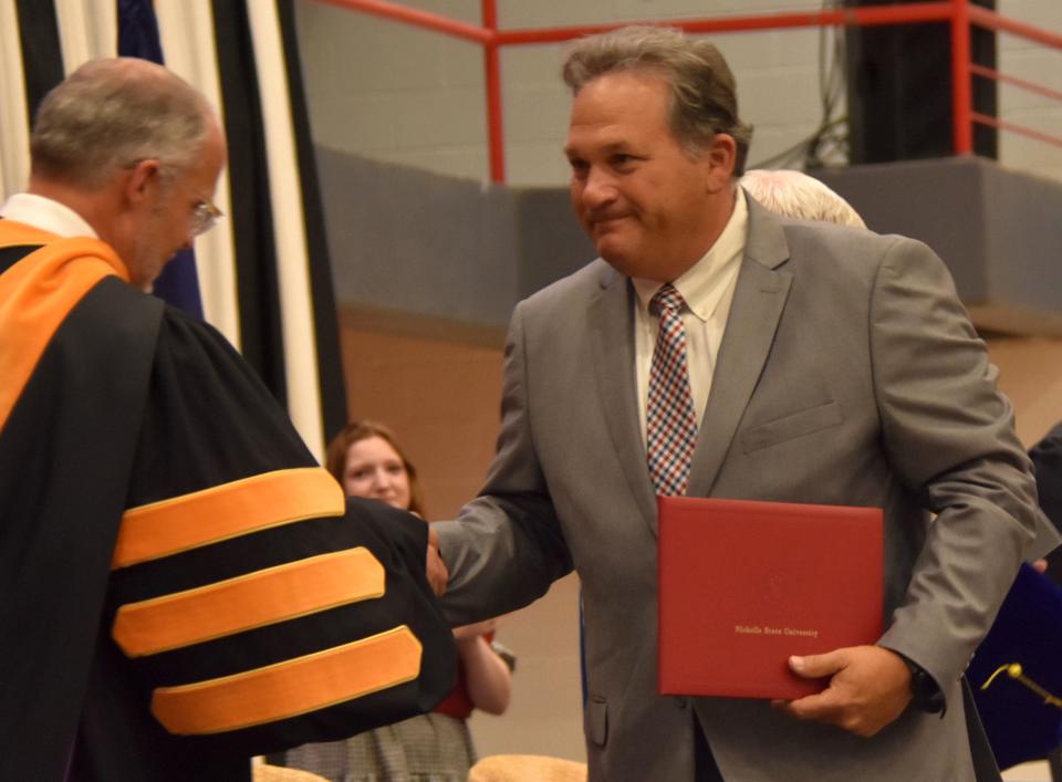 Mike Plaisance receives a diploma during Saturday's graduation on behalf of his son, Hugh Plaisance, 24, a Nicholls student who died by suicide in April.