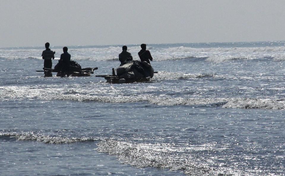 In this Jan. 16, 2017, photo, Rohingya fishermen stand in shallow waters on the coastline waiting to launch their homemade rafts to go fishing in the rough sea of the Bay of Bengal off Tha Pyay Taw village, Maungdaw, western Rakhine state, Myanmar. Every day before sunrise, dozens of fishermen, shivering against the cold, shove out onto the Bay of Bengal on makeshift rafts made out of plastic jugs, bamboo and twine. Their usual, sturdy fishing boats were outlawed three months ago when Myanmar authorities launched a sweeping and violent counter-insurgency campaign in Rakhine state, home to the long-persecuted Rohingya Muslim minority. (AP Photo/Esther Htusan)