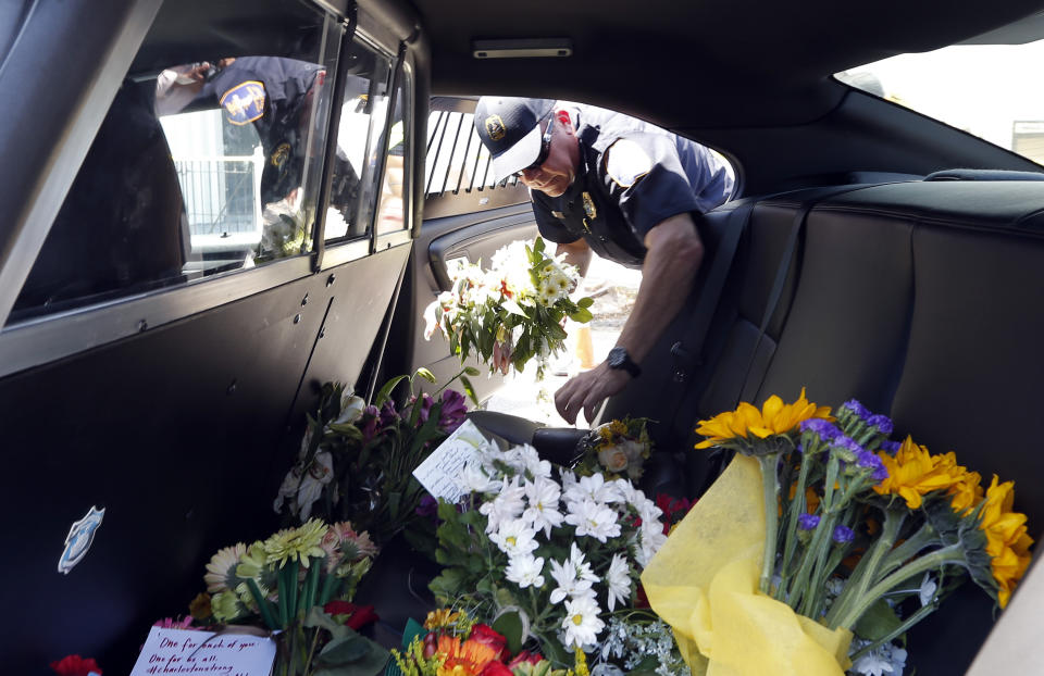 Charleston police Lt. S. Siprko removes flowers from the backseat of a patrol car, Thursday, June 18, 2015 to a makeshift memorial in front of the Emanuel AME Church in Charleston, S.C. T 