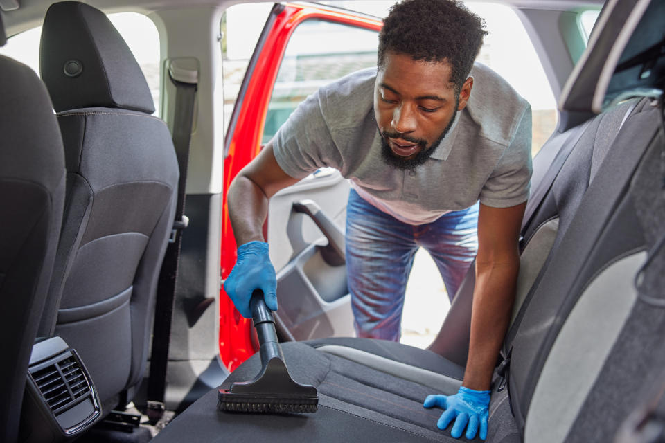 man vacuuming car seat