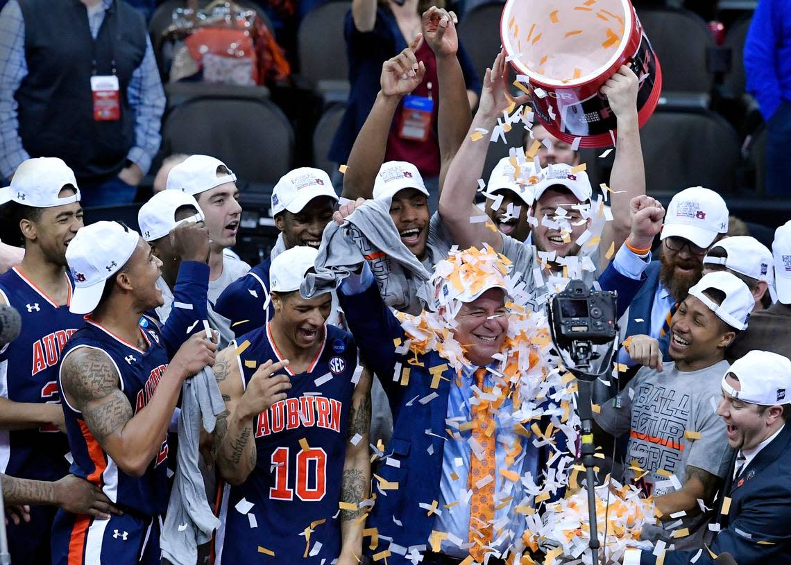 Auburn coach Bruce Pearl, covered in confetti, celebrates with his Tigers after they took down Kentucky 71-77 in overtime in the championship game of the Midwest Region in 2019.