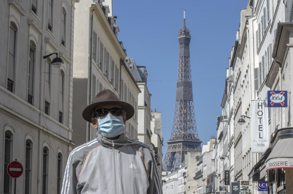 A man wears a mask to protect against the spread of the coronavirus walk in a street close to the Eiffel Tower in Paris, Sunday, April 26, 2020. France continues to be under an extended stay-at-home order until May 11 in an attempt to slow the spread of the COVID-19 pandemic. (AP Photo/Michel Euler)