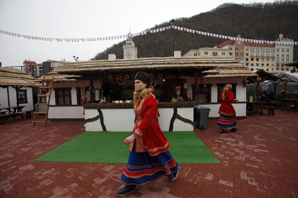 FILE - In this Feb. 22, 2013, file photo, waiters dressed in Russian Cossack costumes work at a street restran in Krasnaya Polyana, mountain Olympic cluster, 60 kilometers East from Sochi, Russia. For visitors to the Winter Olympics, Sochi may feel like a landscape from a dream _ familiar and strange at once. Palm trees evoke a tropical seaside resort, but the Black Sea itself is seriously cold; turn away from the palms and the jagged, snow-covered peaks of the Caucasus Mountains rise nearby. (AP Photo/Alexander Zemlianichenko, file)